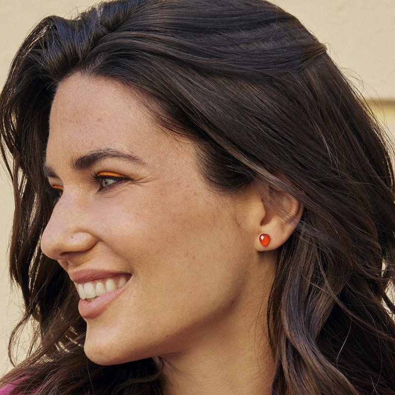 Lächelnde junge Frau mit roten Edelstein Ohrringen